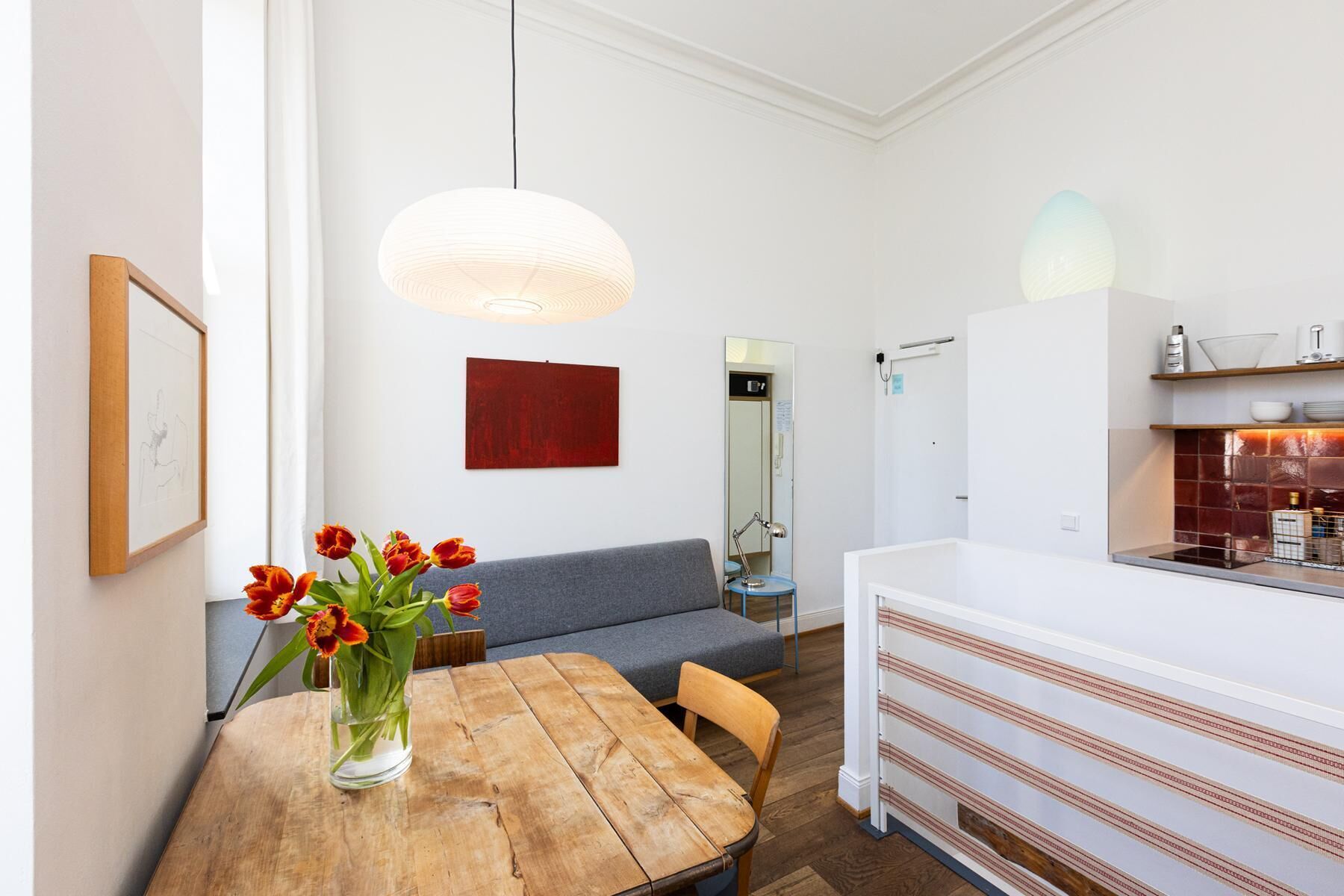 Eine moderne Küche mit weißen Schränken, einem Holztisch und einem grauen Sofa.