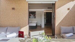 A hotel room with a bed, a sofa, and a table with a glass of water. - Beachfront Studio With Terrace by Wonderful Italy (Genoa)