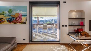 A modern living room with a sliding glass door leading to a balcony with a view of a cityscape. - Beachfront Studio With Terrace by Wonderful Italy (Genoa)