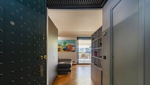 A hallway with a wooden floor, a black door with a grid pattern, a gray sofa, and a mural on the wall. - Beachfront Studio With Terrace by Wonderful Italy (Genoa)