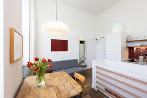 A modern interior with a dining table, a sofa, a kitchen area, and a pendant light.