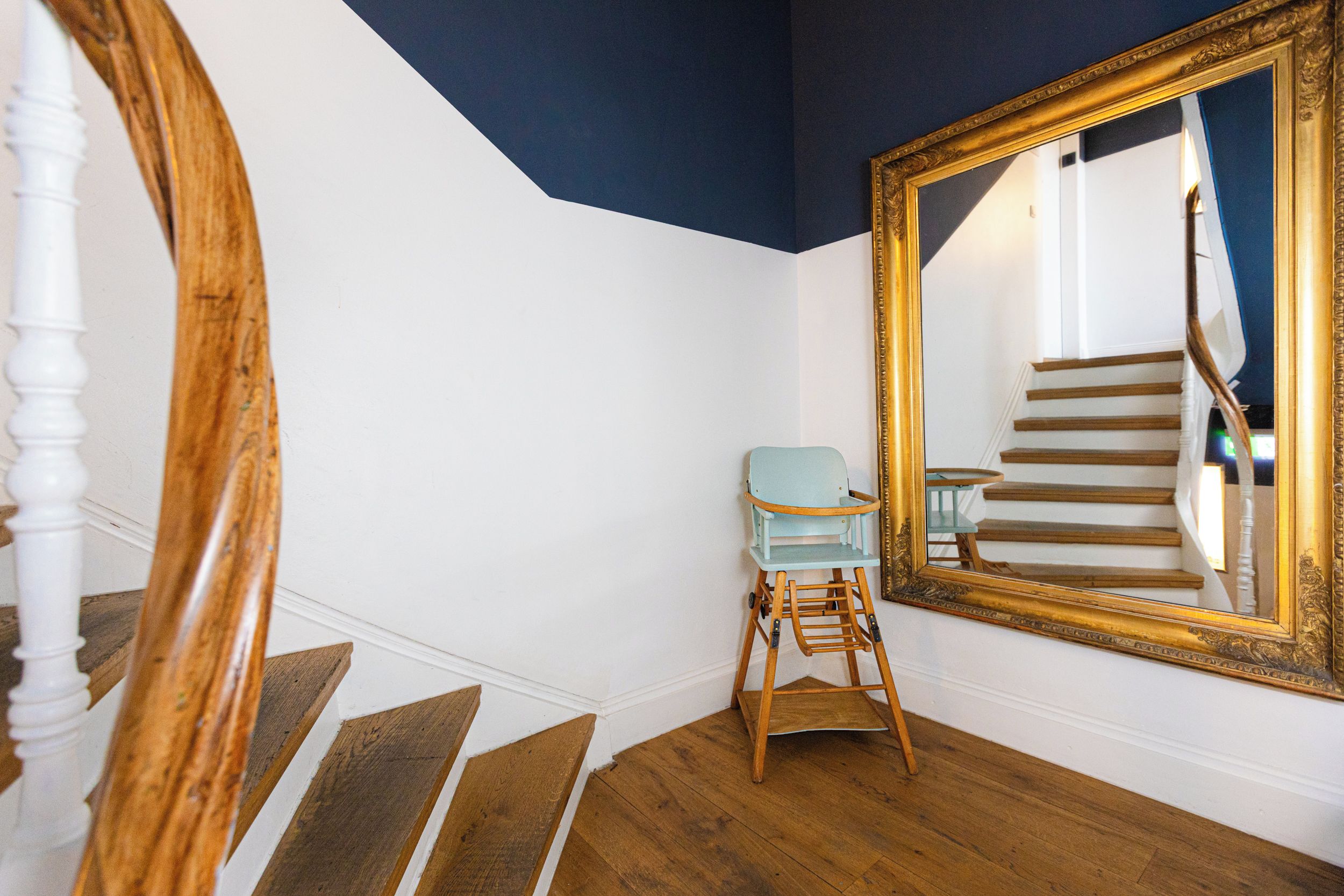 A staircase with wooden steps and a light blue chair in a room with white walls and a dark ceiling.