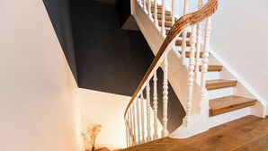 Un escalier avec des balustrades blanches et des marches en bois menant à un palier sombre.