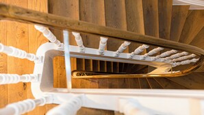 A spiral staircase with a golden handrail and white balusters. - my.statthaus - 8 apartments exclusively for up to 22 people (Köln)