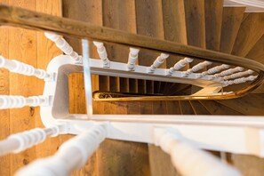 Un escalier en colimaçon avec une rampe dorée et des balustres blanches.
