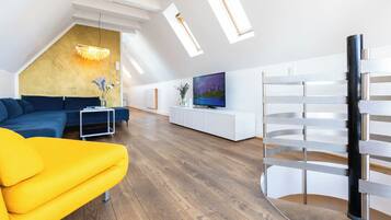 A modern living room with a sectional sofa, a yellow armchair, a TV, and a white entertainment unit.