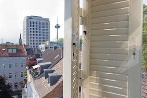 A view of a cityscape with a prominent tower and a building with a grid-like facade. - Cathedral view suite with 2 bedrooms and 2 bathrooms on the 4th and 5th floor (Köln)