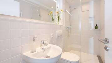 Ein modernes Badezimmer mit Waschbecken, Toilette und einer Duschkabine aus Glas.