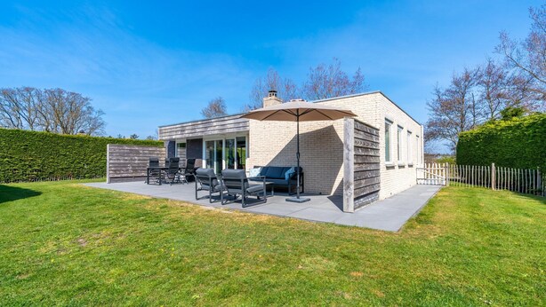 A modern house with a patio, outdoor furniture, and a barbecue area. - Tastefully Furnished Detached Bungalow (De Koog)