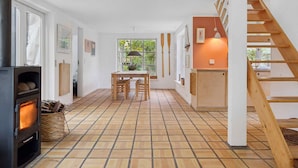 Een modern interieur met een centrale eethoek, een open haard en een houten trap.