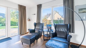 A modern living room with two leather armchairs, a small round table, and a large floor lamp. - Charming Villa Near the sea and Forest (De Koog)