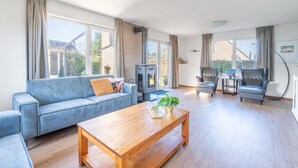 A spacious living room with a blue sofa, a wooden coffee table, and a fireplace. - Charming Villa Near the sea and Forest (De Koog)