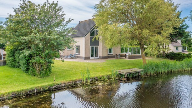 A house with a pond, surrounded by greenery and a small dock. - Charming Villa Near the sea and Forest (De Koog)