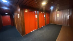A corridor with wooden walls and red doors, leading to multiple rooms. - VAL Thorens Rental: Studio Cabin at the top of the Resort (Les Belleville)
