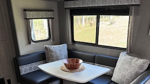 Interior acogedor de una autocaravana con zona de estar, mesa y ventana con vistas al exterior.