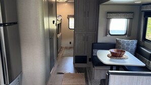 Cocina compacta para autocaravana con una isla central, armarios empotrados y una ventana que proporciona luz natural.