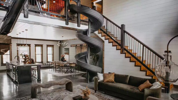 A spacious living area with a spiral staircase, a dining area, and a kitchen. - Movie under Stars, Heated Pool, Pickle ball, Slide (Broken Bow)