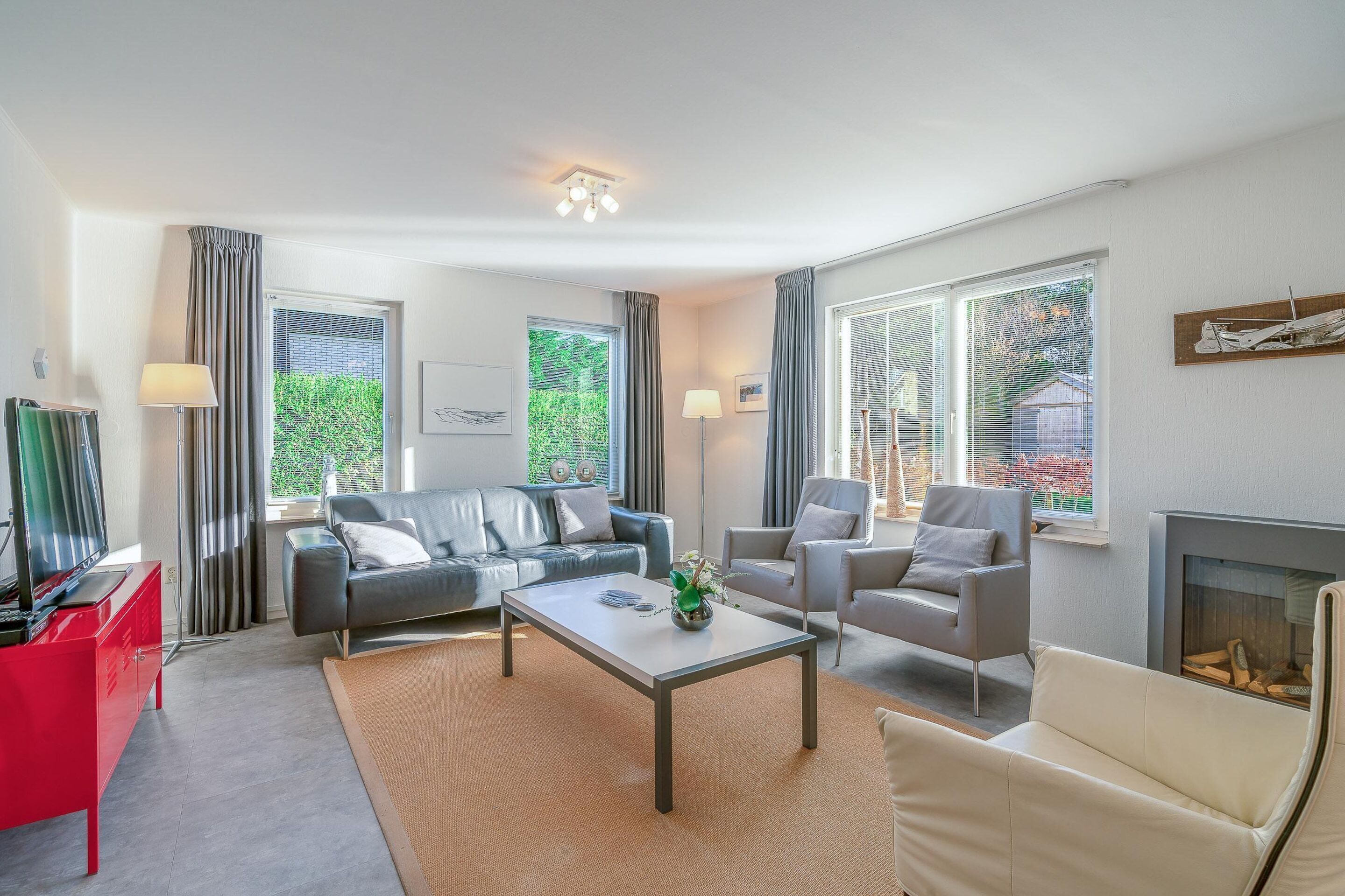 Un salon moderne avec un canapé, des fauteuils, une table basse et une cheminée.