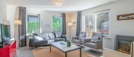 Un salon moderne avec un canapé, des fauteuils, une table basse et une cheminée.