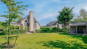 Een modern huis met een ruime tuin, schoorsteen en een overdekte veranda.