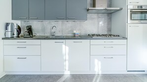 Een moderne keuken met grijze kastjes, een roestvrijstalen afzuigkap, een Bosch oven en een koffiezetapparaat.