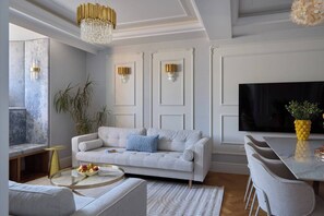 Ein modernes Wohnzimmer mit einer Couch, einem runden Couchtisch, einem Fernseher und einem Essbereich mit Stühlen.
