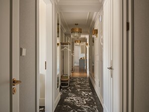 A hallway with a marble floor, white walls, and a hanging chandelier.