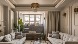 A spacious living room with two sofas facing a central coffee table, a chandelier, and a view through large windows. - Feniks 3-bed Main Square Apartment (Kraków)