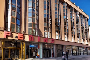 A multi-story building with a prominent 'FEDINE' sign, storefronts, and a bike parked outside.