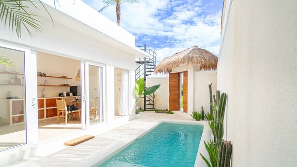 Une maison moderne dotée d’une piscine, de portes-fenêtres coulissantes, d’une structure à toit de chaume et d’un escalier.
