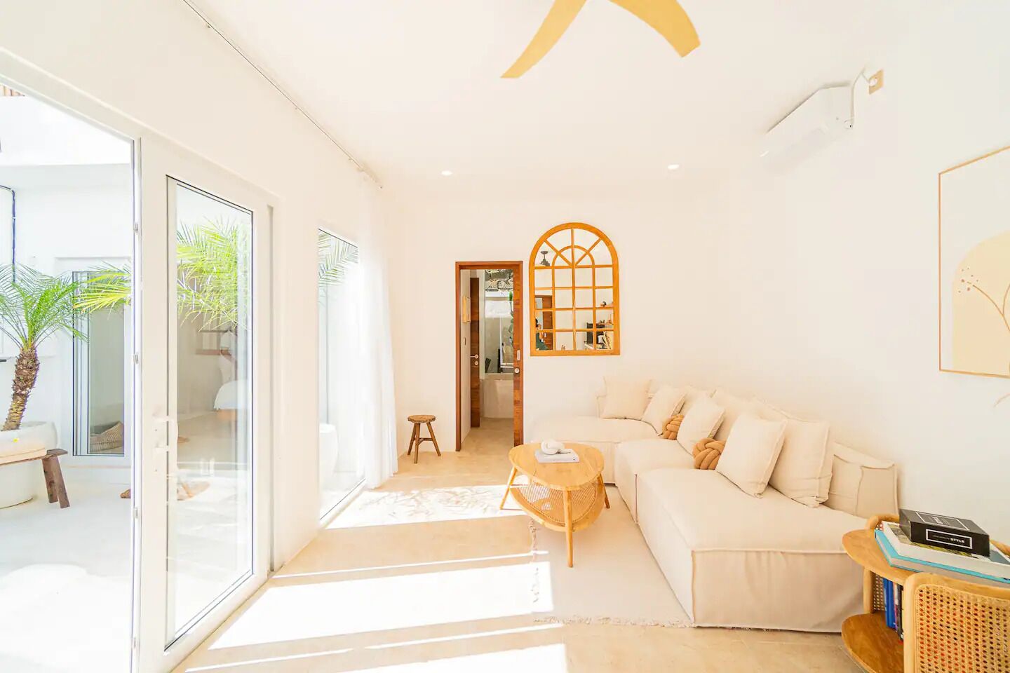 A modern living room with a white sofa, a small round coffee table, and a large window.