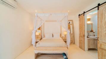 Un dormitorio con cama con dosel, mesitas de noche, un espejo y un armario de madera.