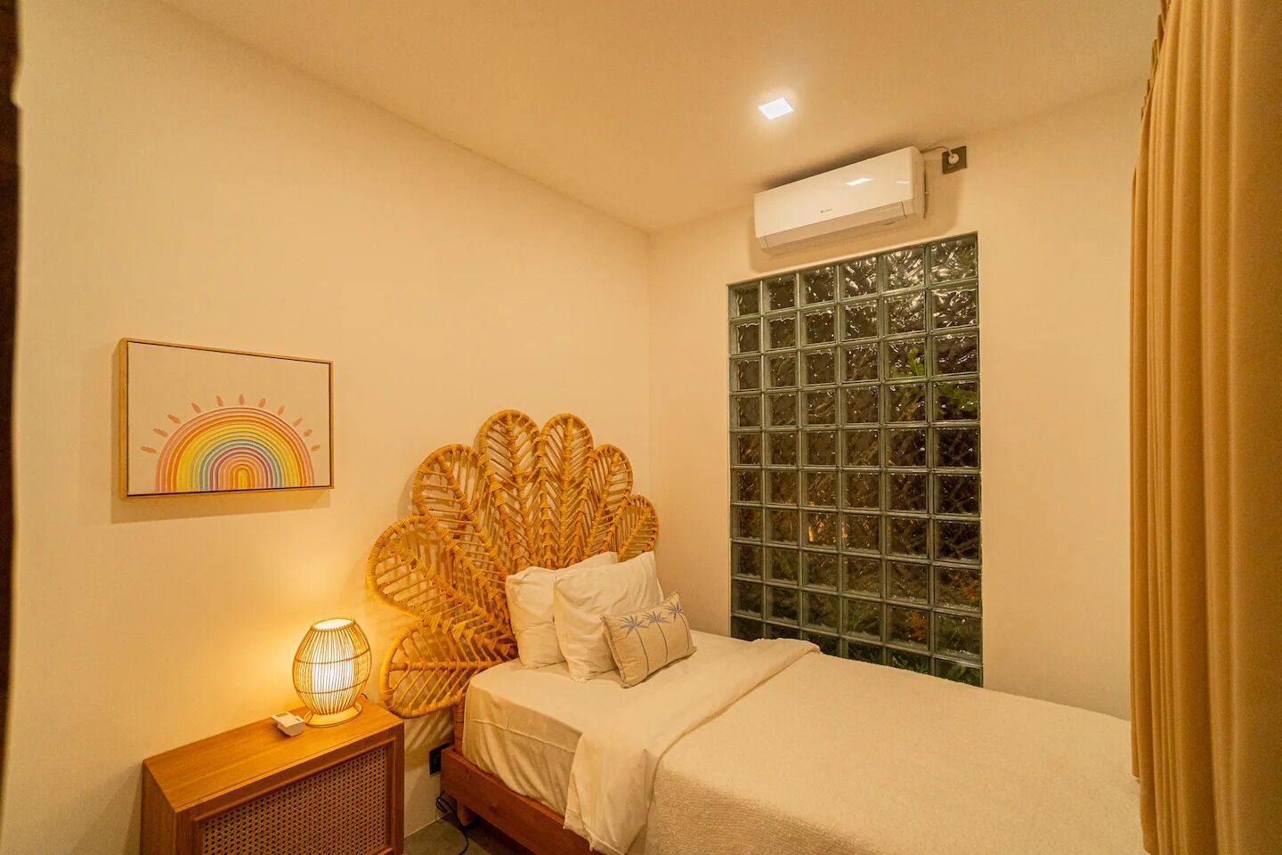 Een slaapkamer met een bed, een bedlamp, een wandairconditioner, een raam met uitzicht en een lijst met een afbeelding aan de muur.