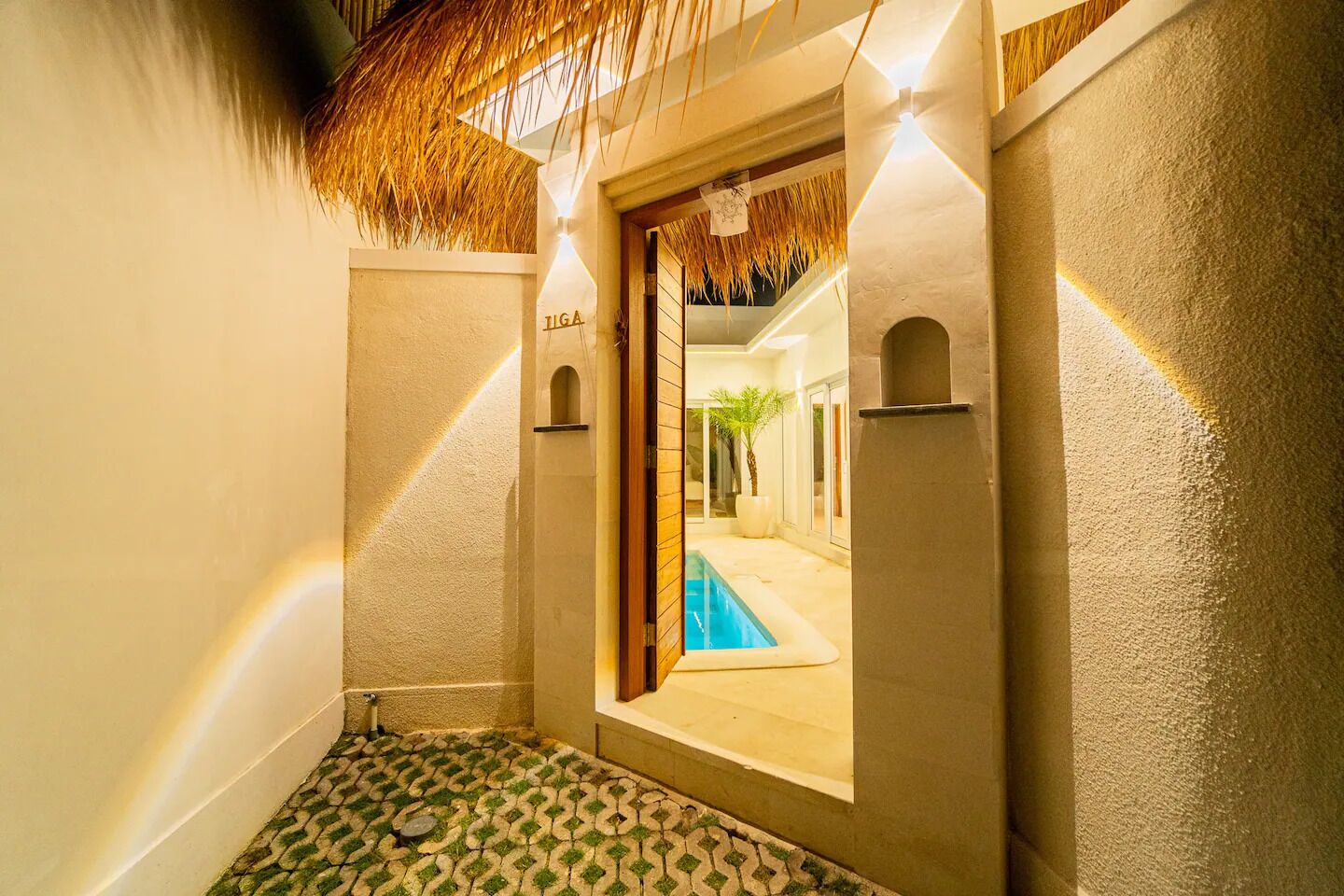 Un pasillo estrecho con una piscina visible a través de una puerta abierta, que conduce a una habitación luminosa.