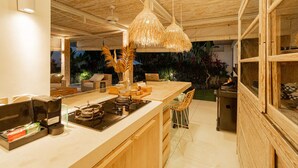 Une cuisine moderne dotée d’un grand îlot central, d’un plafond en bois et d’un luminaire suspendu.