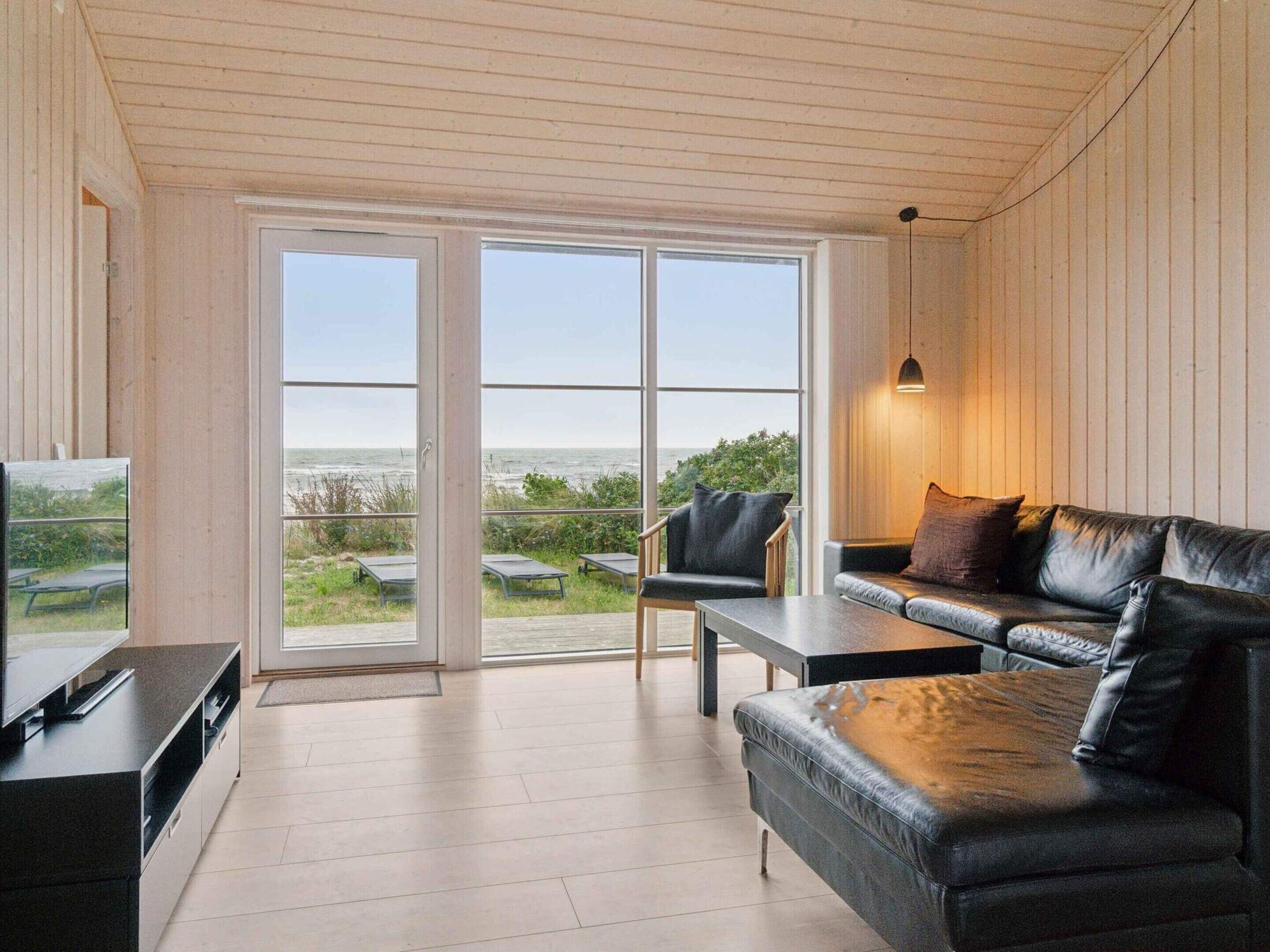 Un salon moderne doté d’une grande porte-fenêtre coulissante donnant sur un balcon avec vue sur la mer.