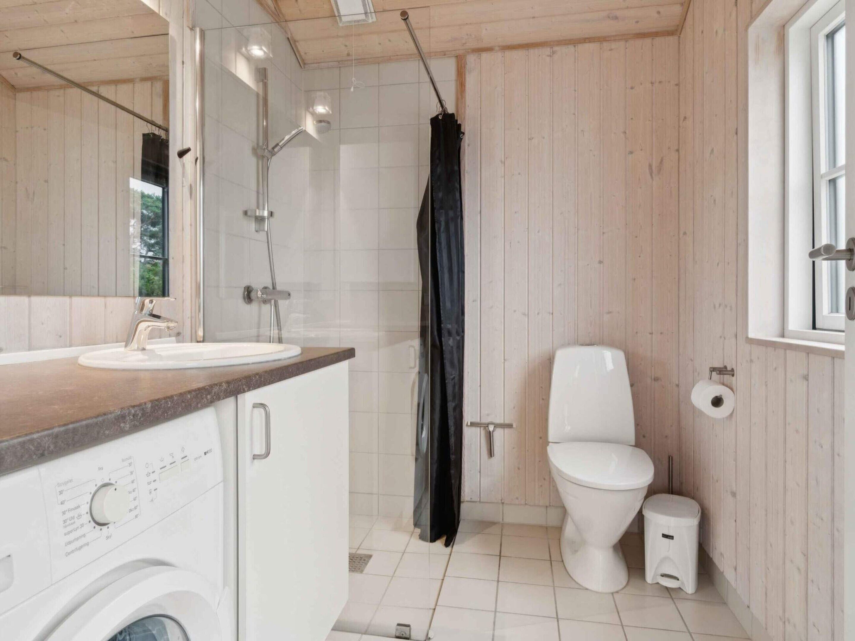 A modern bathroom with a wooden interior, a sink, a toilet, and a shower.