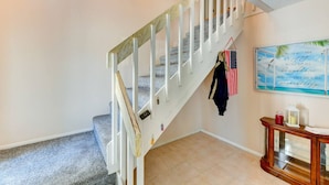A staircase with white railings and a handrail, a wall with a framed quote, and a small wooden console table with a glass top. - The Pelican on Siesta (Siesta Key)
