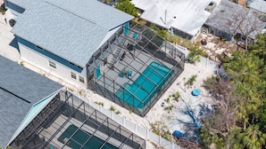 A residential area with two swimming pools surrounded by a metal fence, adjacent to a house with a grey roof. - The Pelican on Siesta (Siesta Key)