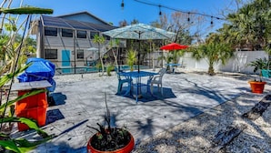 An outdoor patio with a pool, blue and red umbrellas, and potted plants. - The Pelican on Siesta (Siesta Key)