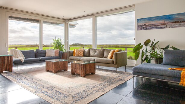 A spacious living room with a large window, a sofa set, a coffee table, and a rug. - Luxe Villa With Pool and Sauna in Spijkerboor (Spijkerboor)