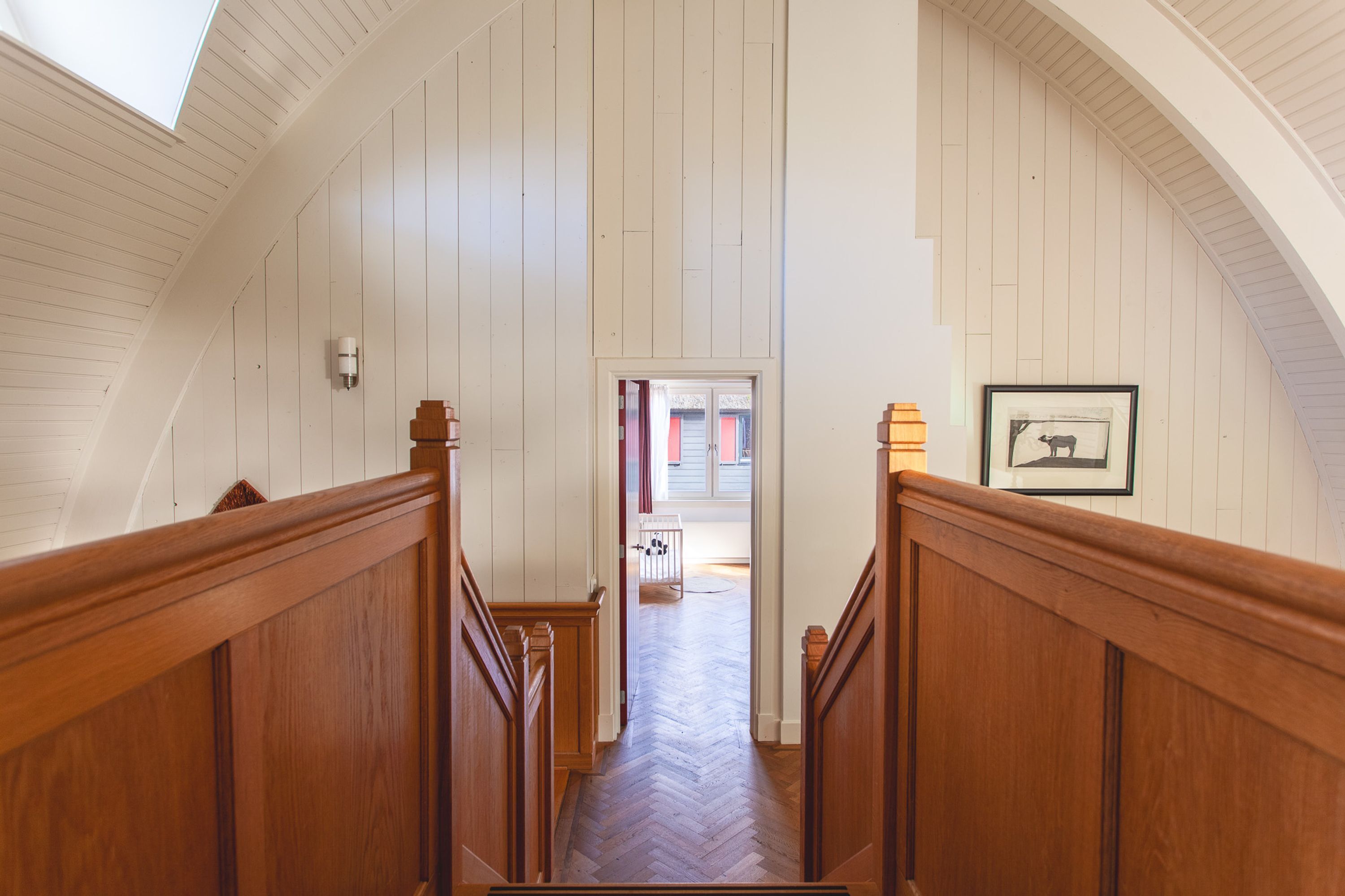 A wooden staircase with a herringbone floor leading to a door.