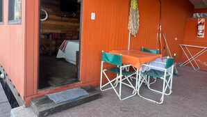 Un edificio pequeño y naranja con un patio de baldosas. Hay una mesa y dos sillas afuera.