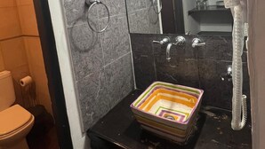 Un baño con encimera negra, espejo, toallero y lavamanos.