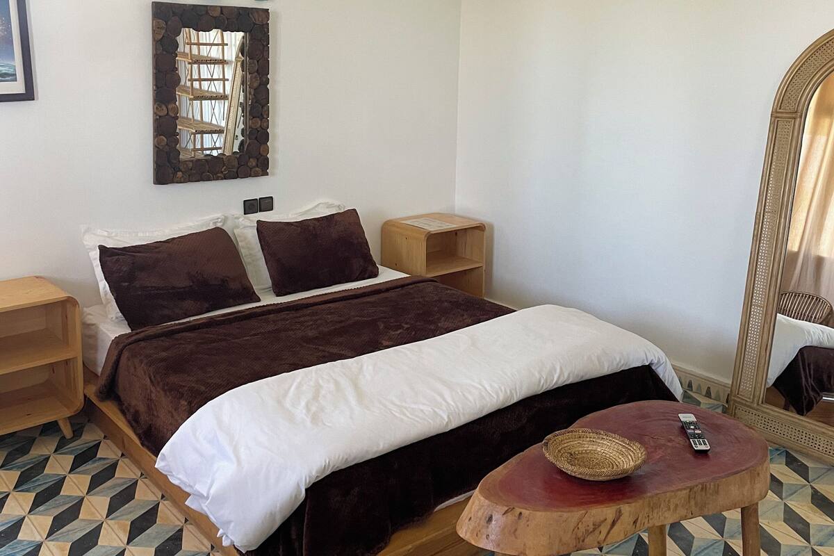 Ein Schlafzimmer mit einem Bett, zwei Nachttischen, einem Spiegel und einem Schild mit der Aufschrift 'HEY' an der Wand.