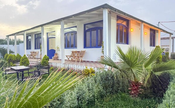 Ein zweistöckiges Haus mit überdachter Veranda, einer Tür und Fenstern.