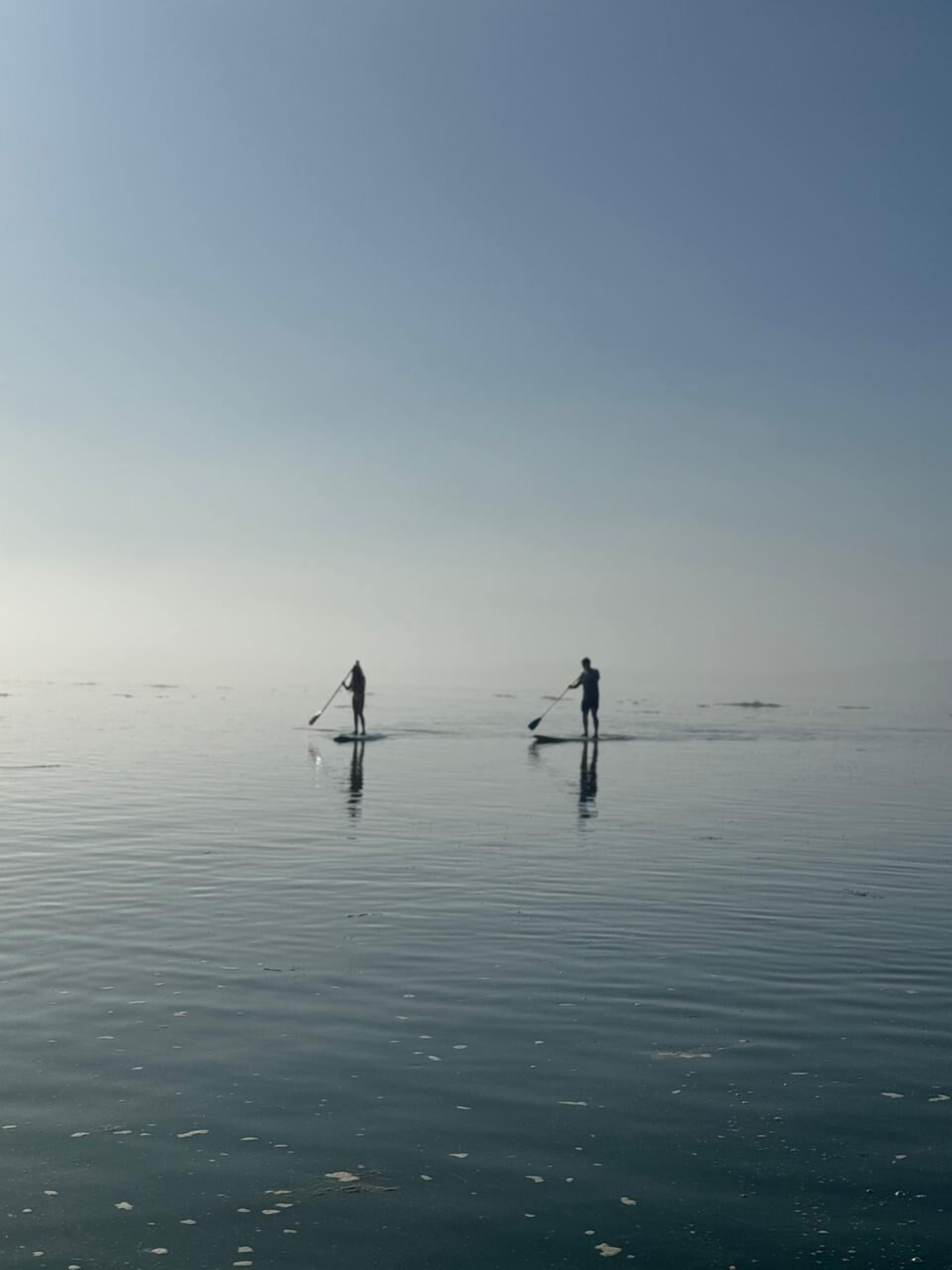 Dos personas sobre un cuerpo de agua tranquilo, probablemente participando en una actividad acuática.