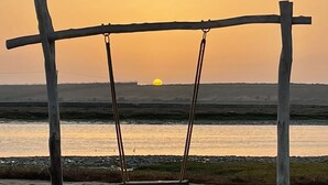 Et legesæt i træ på en sandstrand med solnedgang i baggrunden.