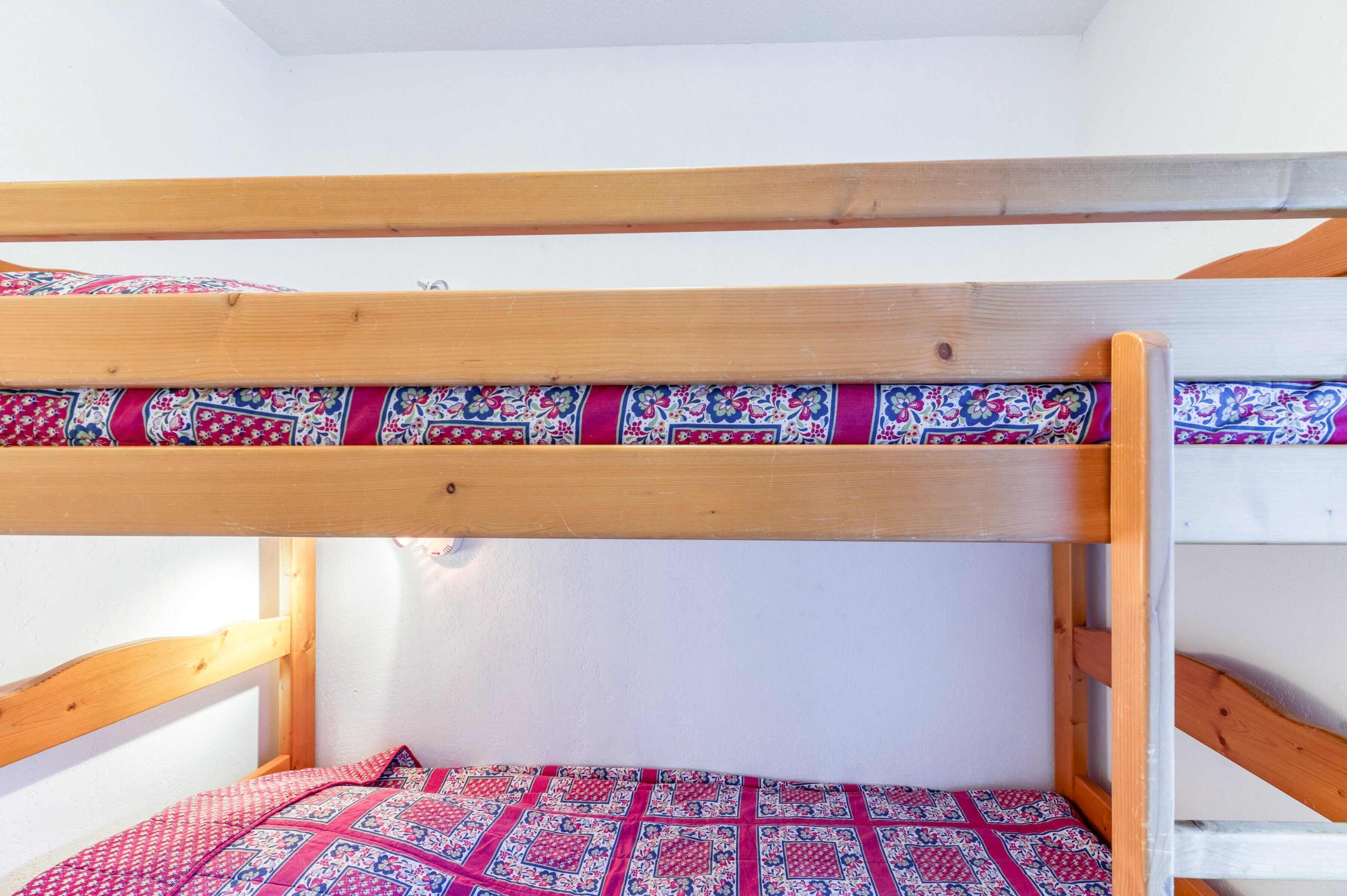 A bunk bed with a patterned bedspread and wooden headboard.
