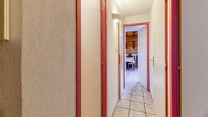A narrow hallway with red-framed doors leading to a room with a wooden ceiling and a dining table. - Apartment "Le Ressoutan" with Mountain View and Balcony (Saint-Colomban-des-Villards)